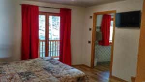 una camera da letto con tende rosse, un letto e una finestra di Le Nid de l'Aigle a Champoluc