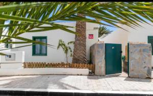a building with a palm tree next to a fence at RockBeach bungalow in Costa Teguise