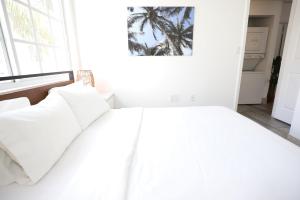 1 dormitorio con 1 cama blanca y una pared con una pintura de palmera en 3 Minute Walk to Beach 2 Bedroom Apartment Family Friendly with No Pet Fee, en Miami Beach