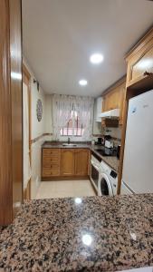 Una cocina con gabinetes de madera y un refrigerador blanco. en Mediterráneo Gourmet Stays, en Oropesa del Mar