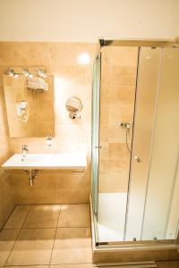 a bathroom with a shower, sink, and toilet at Hotel City Bell in Prague