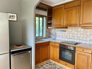 a kitchen with wooden cabinets and a refrigerator at Les Ondes - Terrasse RdC Villa Calme Parking Proche Plage in Antibes