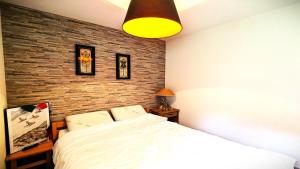 a bedroom with a white bed and a brick wall at Résidence Les Cytises - Agréable T2 vue montagne 4/6 personnes MAE-4471 in Vallouise