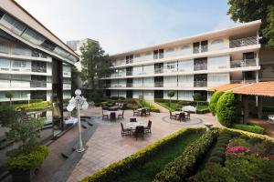 an apartment building with tables and chairs in a courtyard at Krystal Satelite Maria Barbara in Mexico City