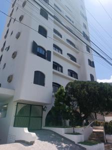 a tall white building with a tree in front of it at Apartamento Guarujá Pitangueiras in Guarujá