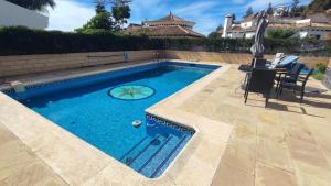 a swimming pool with a table and chairs next to a house at Villa Arte de Aguilas in El Palo