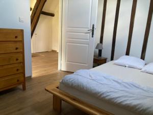 a bedroom with a bed and a dresser and a door at La maison des fleurs in Saint-Arnoult