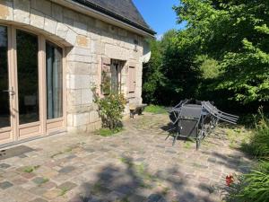 a patio with a table and a bench next to a building at La maison des fleurs in Saint-Arnoult