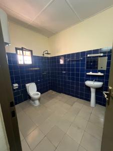 a blue tiled bathroom with a toilet and a sink at Résidence huele in Ouagadougou +17 photos