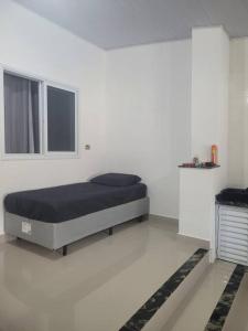 a bedroom with a bed in a white room at Casa com piscina Itanhaém in Itanhaém