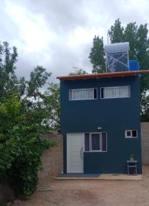 Una gran casa azul con un garaje blanco en Dpto Evelyn, en Villa Cura Brochero