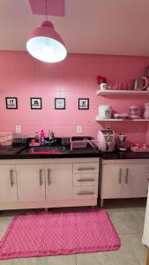 a pink kitchen with a sink and a pink wall at Apartamento rosa in Guarapari