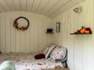 a bedroom with a bed in a room with white walls at Charming shepherds hut with hottub in Umberleigh Bridge