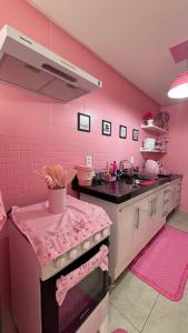 a pink kitchen with a sink and a stove at Apartamento rosa in Guarapari