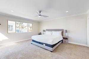 a white bedroom with a bed and a window at Palm Tree Getaway in Newport Beach