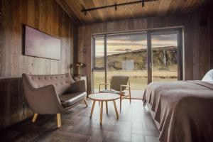 a bedroom with a bed and a chair and a window at Seljalandsfoss Horizons in Hvolsvöllur