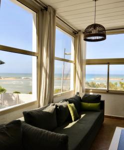 a living room with a couch and large windows at Maison Simonetta in Oualidia