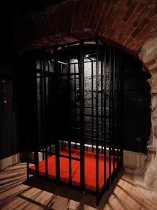 カウナスにあるFETISH Roomの部屋の中に赤いベッドが置かれた黒いケージ