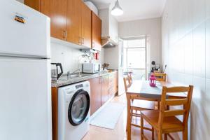 cocina con lavadora y mesa con sillas en Divine House of Graça, en Lisboa