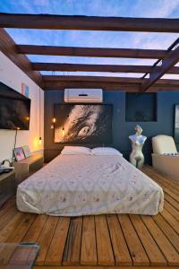 a bedroom with a large bed with a painting on the wall at Residencial Vale do Sol in Garopaba