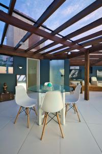 a dining room with a glass table and white chairs at Residencial Vale do Sol in Garopaba