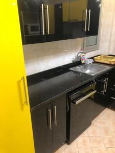 a black kitchen with a sink and a mirror at Chilling home in Madinaty