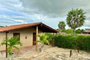 a house with palm trees in front of it at Casa SRBG - 2 Quartos com Ar - 150m da Praia in Barra Grande