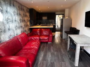 a red couch in a living room with a kitchen at Central City Living - Stylish & Spacious 5 Bedrooms in Parkside