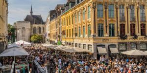 a crowd of people in a street in front of buildings at Locatif gare Lille Europe Souvenir in Lille