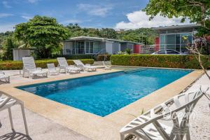 a swimming pool with white chairs and a house at Oceantide Playa Hermosa in Playa Hermosa