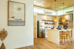 a kitchen with a refrigerator and a counter with stools at Oceantide Playa Hermosa in Playa Hermosa