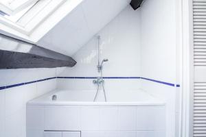 a white bathroom with a bath tub in a attic at Hotel des Arts - Cite Bergere in Paris
