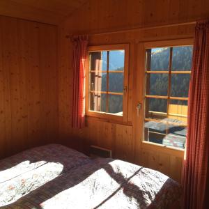 a bedroom with a bed and two windows in it at Chalet Annika in Grimentz