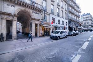 a woman walking down a city street with a van at Hotel des Arts - Cite Bergere in Paris +20 photos