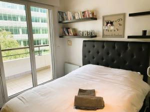 une chambre avec un lit avec une tête de lit noire et une fenêtre dans l'établissement LE PARADIS - 2 chambres, balcon, parking, à Boulogne-Billancourt