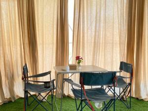 a table with three chairs and a vase of flowers at Breathe Wild in Phumĭ Pu Rôdêt Leu