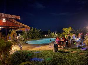 a group of people sitting around a table by a pool at night at Breathe Wild in Phumĭ Pu Rôdêt Leu +16 photos