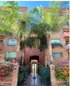 a building with palm trees in front of it at Bel Appartement meublé avec Piscine, l'hivernage à Marrakech in Marrakech