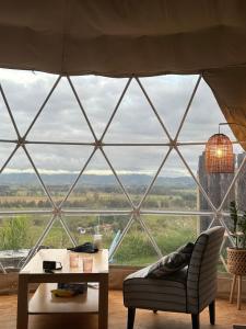 a room with a large window with a table and a chair at Waipū Thunder Domes no.1 offgrid eco glamping dome in Waipu