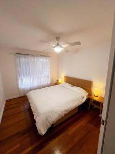 a bedroom with a white bed and a ceiling fan at Holiday Home in Lakes Entrance! in Lakes Entrance