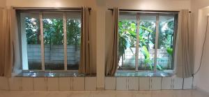 two windows with curtains in a room at Ecoark Farmstay in Cuncolim +70 photos