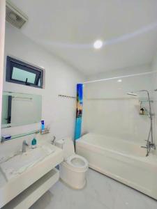 a bathroom with a toilet and a tub and a sink at Apec Sunsea Homestay in Liên Trì (3)