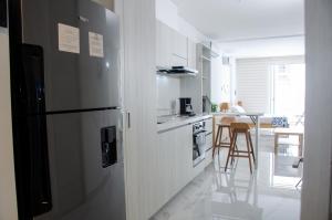 a kitchen with a refrigerator and a table with chairs at Nuevo Loft con vista al mar a pocos pasos de la playa in Santa Marta