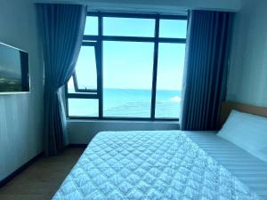 une chambre avec un lit et une grande fenêtre dans l'établissement Beachfront Hon Chong Holtel & Apartment, à Nha Trang