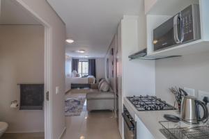 a kitchen with a stove top oven next to a living room at The Millennial Cosy stay in Durban