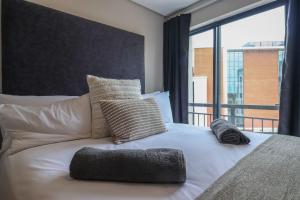 a white bed with pillows and a large window at The Millennial Cosy stay in Durban +14 photos