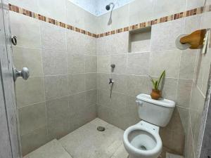 a bathroom with a toilet and a shower with a plant at Dicha Perfecta Telchac in Telchac Puerto +2 photos