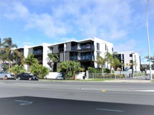 un edificio bianco con palme di fronte a una strada di Sunset Apartment, Mount views, POOL, GYM, HOT TUB a Mount Maunganui