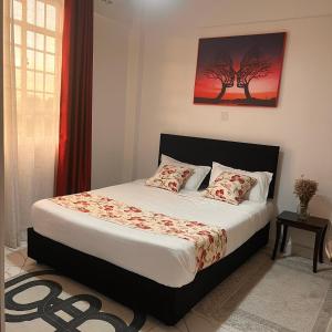 a bedroom with a bed with a tree painting on the wall at Koselig California in Nanyuki