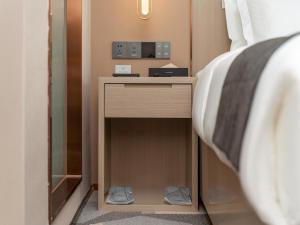 a nightstand next to a bed in a room at Lavande Hotel Credit Building of Gaocheng District, Shijiazhuang City in Dongliucun